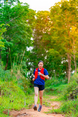 Fototapeta na wymiar Asian female trail runners, wearing runners, sportswear, practice running on a dirt path in a forest. With a happy mood, there were many green trees in the background.