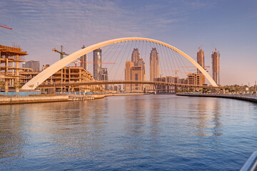Tolerance bridge and promenade embankment along Dubai Creek Canal with large construction site