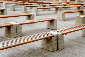 Empty benches made of wood and concrete with traces of restrictive tapes.