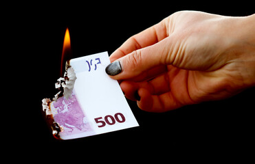 Five hundred Euros are burning with fire in hand isolated on black