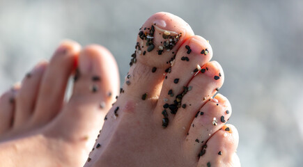 Legs of a girl on a pebble beach.