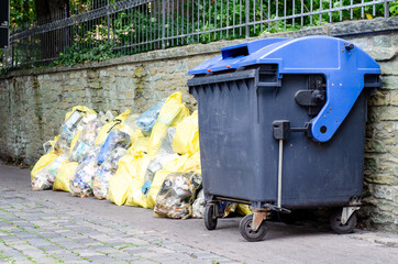 Plastic outdoor dumpsters and garbage bag with garbage.
