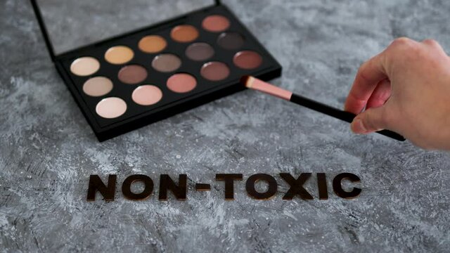 low tox and natural beauty products, make-up palette with non-toxic text on grey background