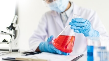 Fototapeta premium scientists researching in laboratory in white lab coat, gloves analysing, looking at test tubes sample, biotechnology concept