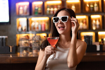 Nightlife concept a sexy girl wearing sunglasses looking mysterious with a straight face holding a drink with cherry on the top