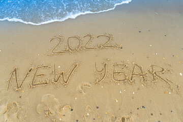 The numbers 2022 are written on a sandy seashell beach. Wave and surf. Summer New Year 2022. Vacation, resort and recreation. Nature. Sea coast
