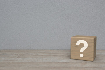 Question mark sign flat icon on block cube on wooden table over white wall background, Business...