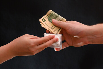 Drug dealer passes a dose to a merchant, sachets of powder on a black background.