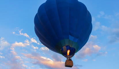 Naklejka premium Balloon Festival Montgolfier, close-up of a bright blue hot air balloon in the air against a blue sky with beautiful pink clouds at sunset, backgrounds, wallpapers, there is copy space in the foto