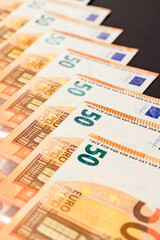 Diagonal line of euro notes isolated on black background, salary in euros.