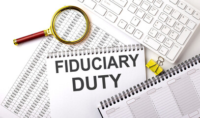 FIDUCIARY DUTY text written on notebook on chart with keyboard and planning
