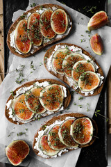 toast with figs, cream cheese and thyme on a black plate on the breakfast table, healthy vegetarian snack or dish, white background, close up, top view, flat lay