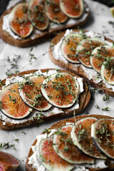 toast with figs, cream cheese and thyme on a black plate on the breakfast table, healthy vegetarian snack or dish, white background, close up, flat lay