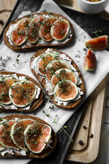 toast with figs, cream cheese and thyme on a black plate on the breakfast table, healthy vegetarian snack or dish, white background, close up, flat lay