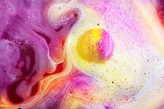 Dissolving color bath bomb in water, closeup.