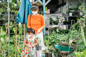 Mother and daughter wearing protective face mask walking at tree shop.