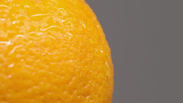 Macro-plan of orange peel on a gray background. A wet orange peel with a drop of water running down it