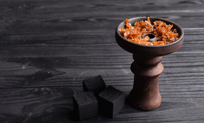 Hookah bowl with tobacco and charcoal for smoking on a dark background. Space for text. Banner

