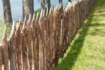 Eco wooden fence with sharpened sharp logs on green grass