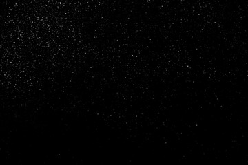 Falling snow on a black background. small particles with bright dots starry sky. Сhaotic white bokeh. light spots texture. abstract.