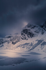 Dramatic cloudscape over Kościelec Peak, High Tatra Mountains, Poland. Czarny Staw Gąsienicowy in the valley. Selective focus on the rocks, blurred background.