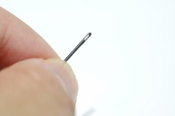 close up of hand holding a sewing needle
