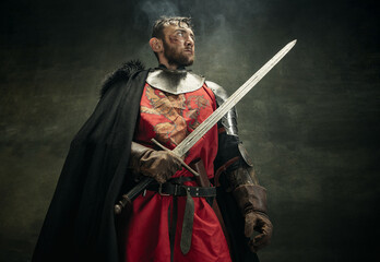 One brutal bearded man, medeival warrior or knight with dirty wounded face holding sword. - obrazy, fototapety, plakaty