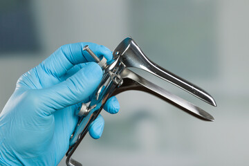 close-up of doctor's hand in medical gloves adjusting a  speculum