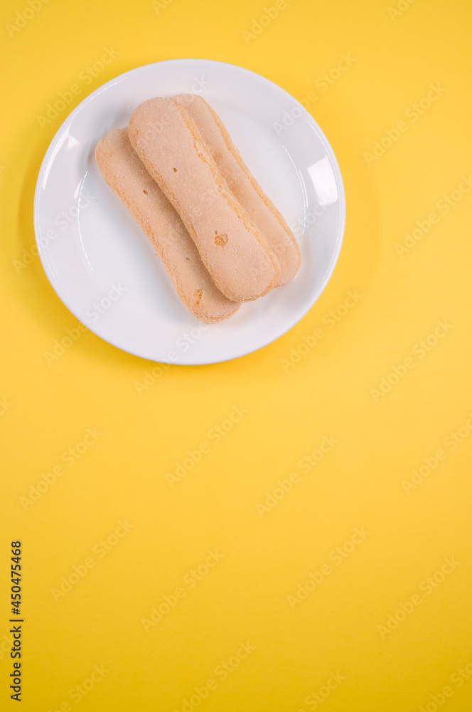 Sticker vertical shot of ladyfinger cookies on a plate isolated on gray background