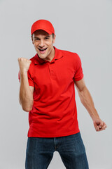 Naklejka premium Young delivery man wearing uniform screaming while making winner gesture