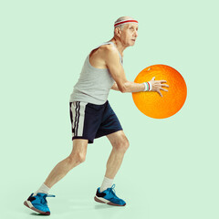 Fit senior man training with fruit on light background. Male basketball player with orange fruit as...