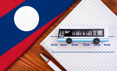 Toy bus and flag of Laos. Travel concept