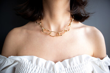Young brunette woman with gold chain necklace. Close up detail of a beautiful necklace. Fashion...