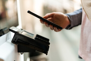 Woman using mobile phone while buying ticket at station