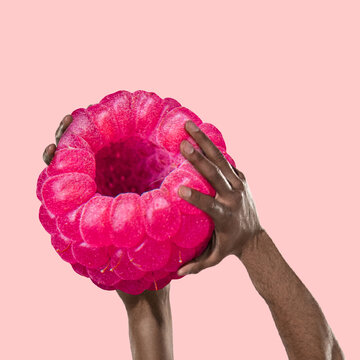 Naklejka Composition with huge raspberry and human strong hands holding it. Healthy eating concept. Art collage