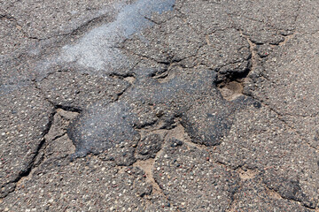 an asphalt road with a lot of holes and damage