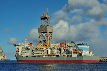 Drilling ship moored in port with a cloudy day.