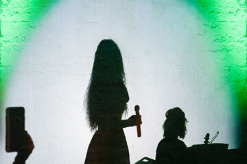 Silhouette of fashionable woman with microphone and musician orchestra member with bow and violin,...