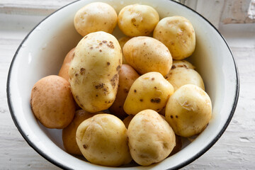 Fresh raw washed organic potatoes in bowl at window sill