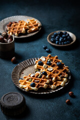 Freshly made belgian waffles with blueberry and hazelnut. Waffles with honey and berry. Place for text. Copy space. Classic sweet breakfast