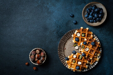 Freshly made belgian waffles with blueberry and hazelnut. Waffles with honey and berry. Place for text. Copy space. Classic sweet breakfast