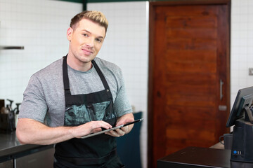 portrait male barista using tablet and in coffee shop