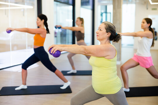 Sporty women doing exercises with pilates balls during group training at gym