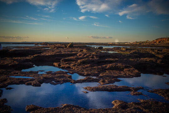 bonito paisaje del mar lleno de rocas con un cielo azul ba&ntilde;ado por los rallos de sol
