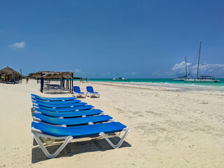 Cayo Guillermo, Cuba, 16 may 2021: Nice view of Pilar beach with white sand and azure ocean against the blue sky. Blue sun loungers are installed in a row for tourists to relax on the beach.