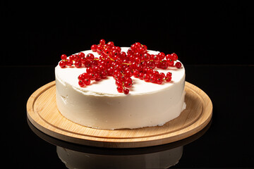 White mousse cake on black backdrop and currant decoration