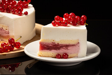 White mousse cake on black backdrop and currant decoration
