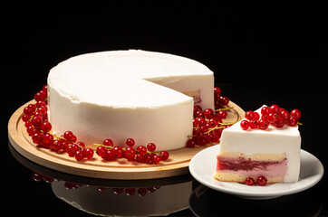 White mousse cake on black backdrop and currant decoration