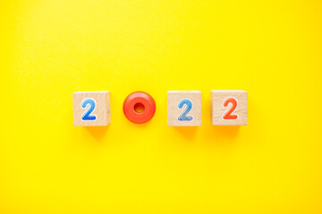 Numbers 2022 from childrens cubes and toys on a bright yellow background. New Year. High quality photo