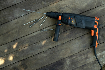 Top view of hammer drill and set of drills on the wooden table.Empty space.Natural sun light